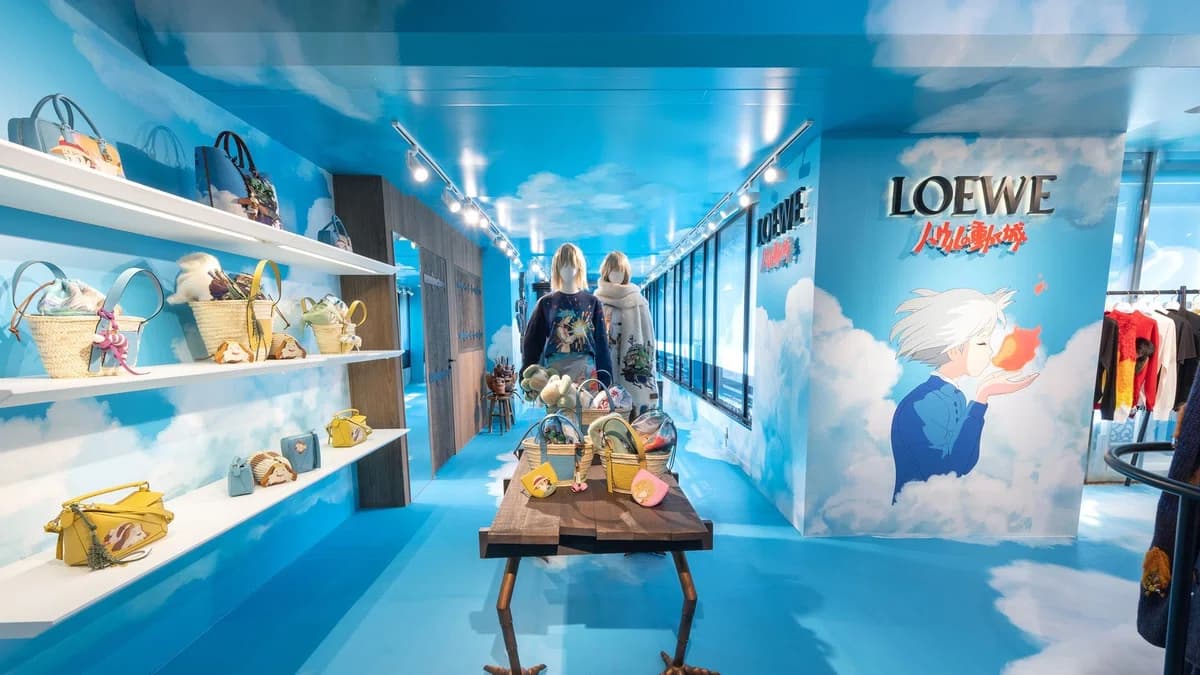 Interior of the LOEWE × Howl’s Moving Castle pop-up with sky‑blue walls, clouds, and shelves filled with bags featuring characters like Howl and Calcifer.