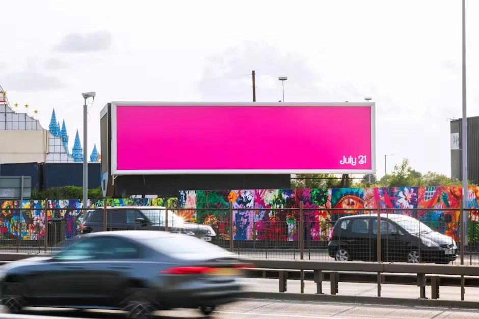 A minimalist bright-pink billboard with only the text “July 21,” teasing the Barbie movie’s release date against an urban backdrop.