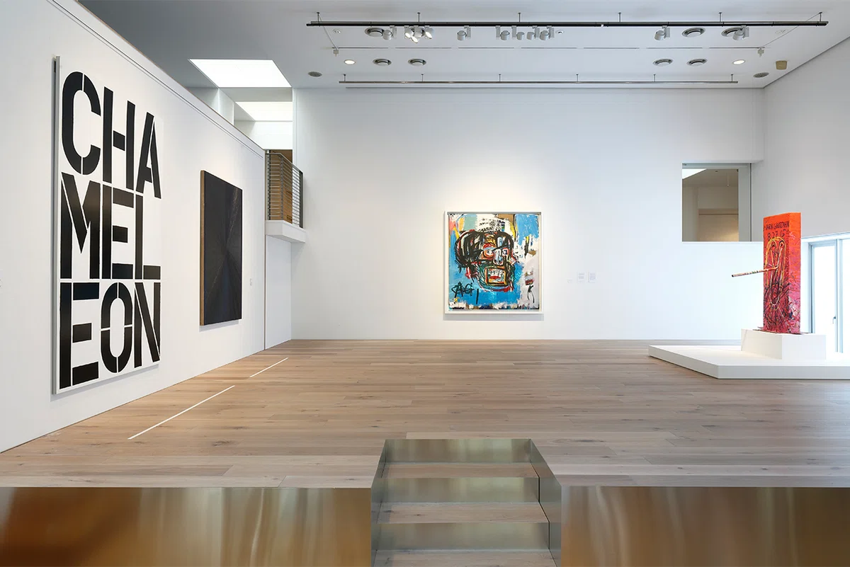 Minimal white Japanese gallery space with contemporary paintings hung on high walls and wooden flooring.